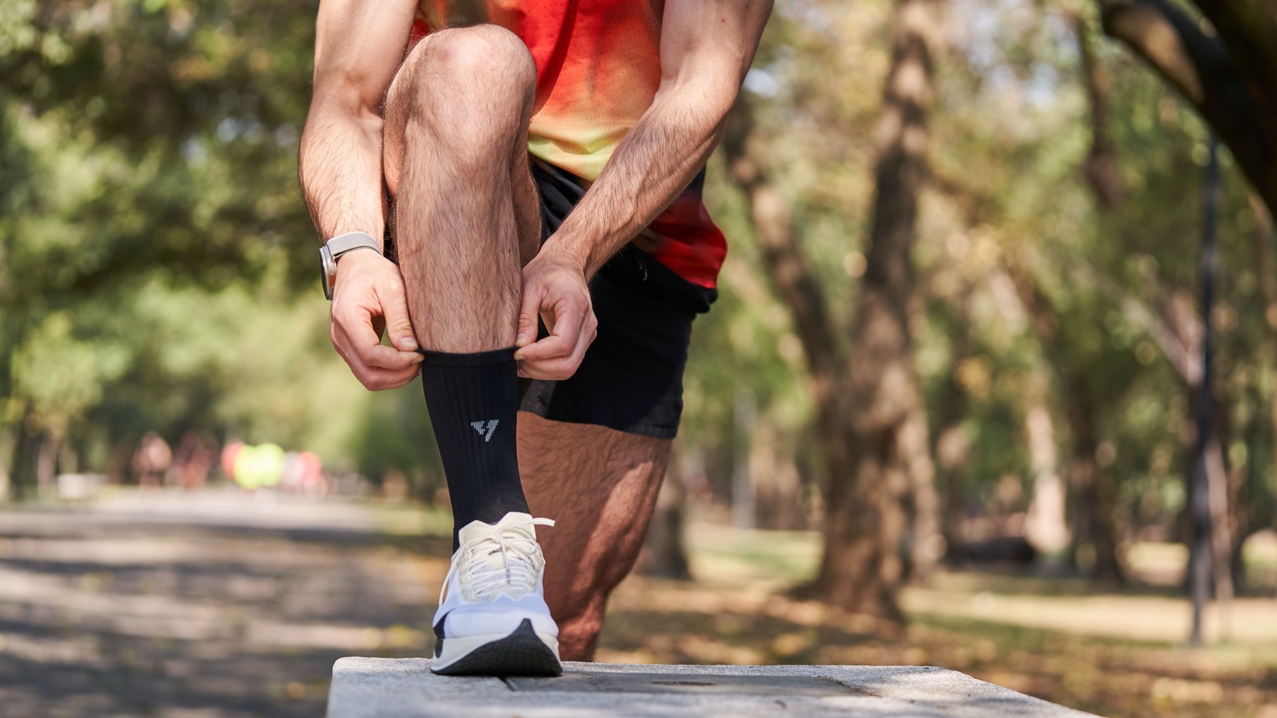 Runner pulling up a black crew sock before a run