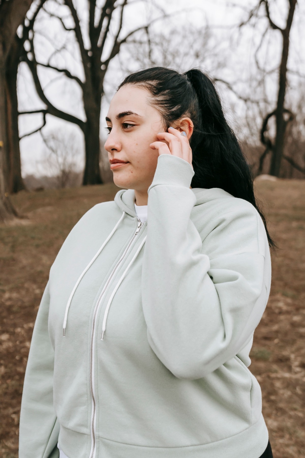 Woman wearing a light grey zip hoodie outdoors