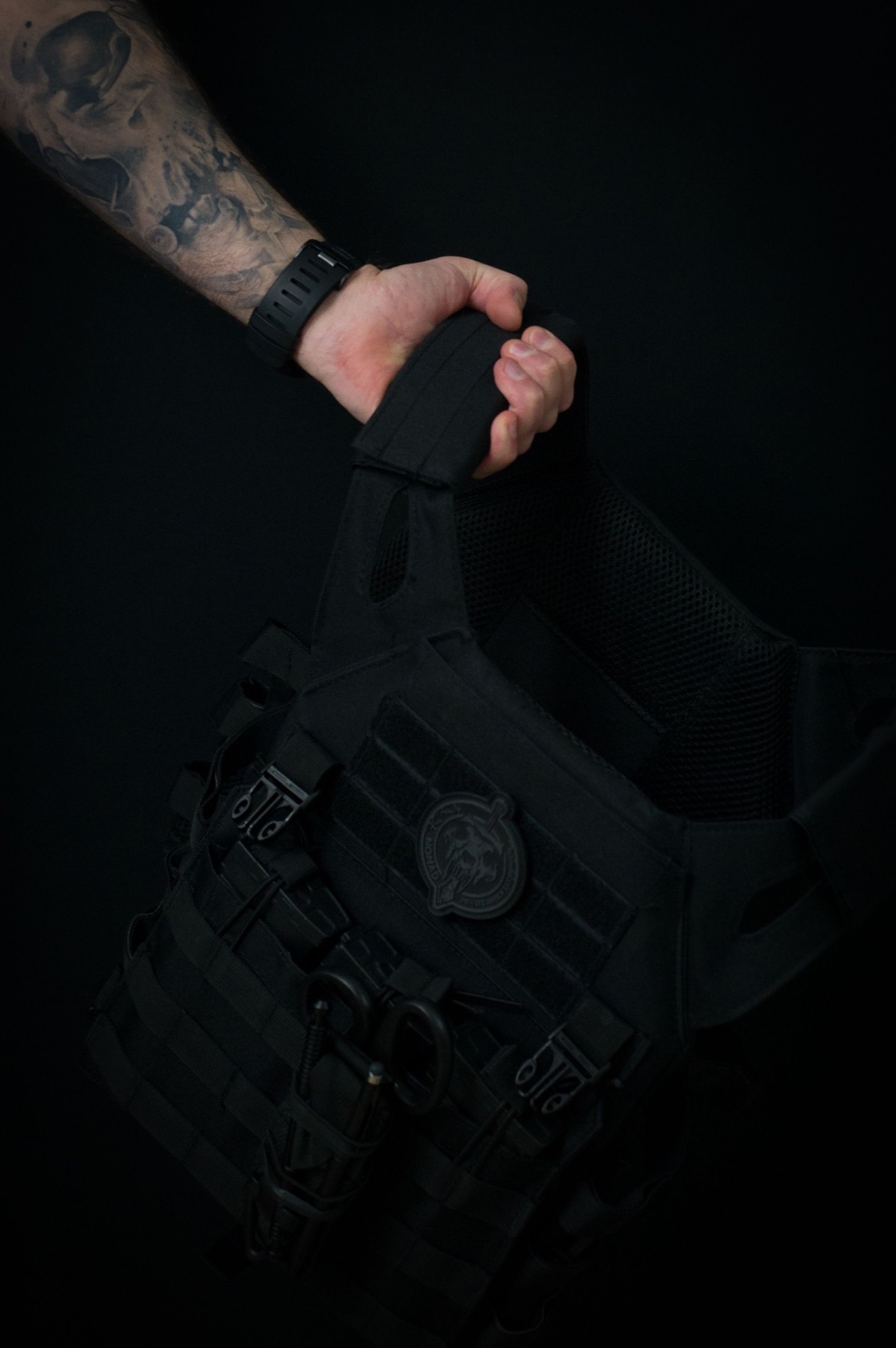 Lifter holding a weighted vest in a dark gym
